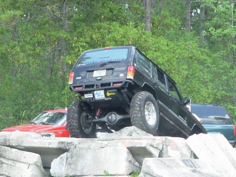1989 Ford Bronco - Modified Jeep Cherokee XJ navigates concrete obstacles, with another vehicle visible behind.