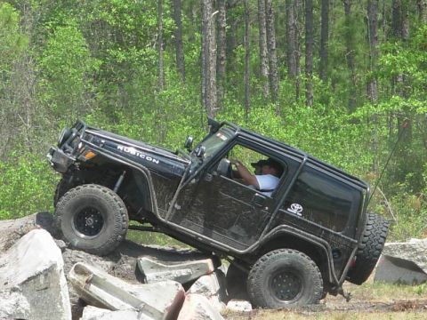 1989 Ford Bronco - A black Jeep Wrangler Rubicon navigates a rocky obstacle course.