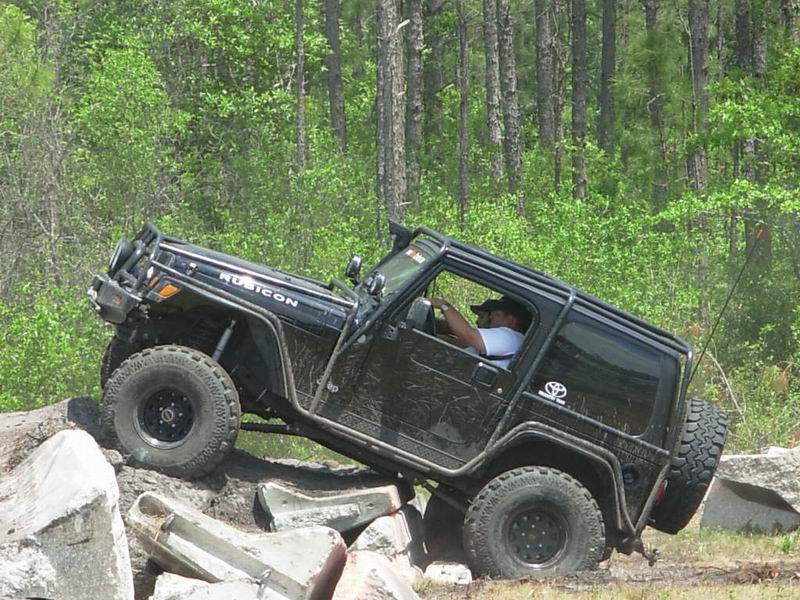 Black Jeep Wrangler Rubicon with off-road modifications climbing over rocks