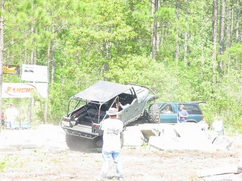 1989 Ford Bronco - Two off-road vehicles navigate an obstacle course in a wooded area.