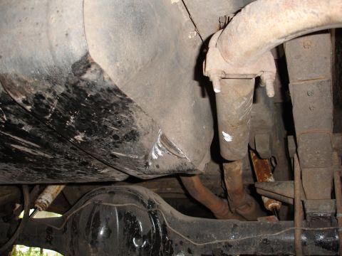1989 Ford Bronco - The underside of a vehicle, focusing on the fuel tank and exhaust components, reveals signs of age and use.