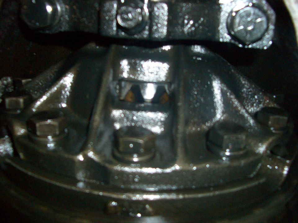 Close-up of a greasy differential gear assembly with visible bolts and internal gears