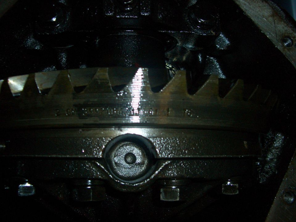 Differential gear with visible teeth and bolts, dark oily interior