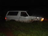 1994 Ford Bronco - 1994 Ford Bronco sits in grass at night with its headlights illuminated.
