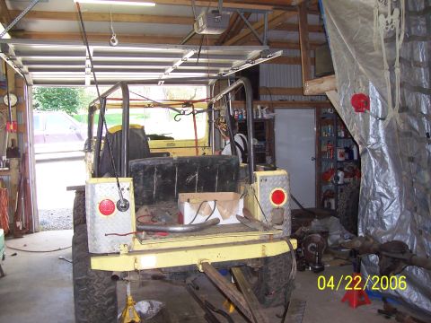 1982 Ford Customline - A yellow Jeep CJ-5 is parked inside a garage, showing its rear end and roll cage structure.