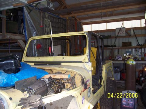 1982 Ford Customline - A yellow jeep is parked in a garage, with its hood open and doors removed, revealing its interior and engine components.