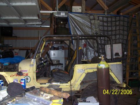 1982 Ford Customline - A yellow Jeep CJ, modified with a roll cage, sits in a garage with various tools and equipment around it.