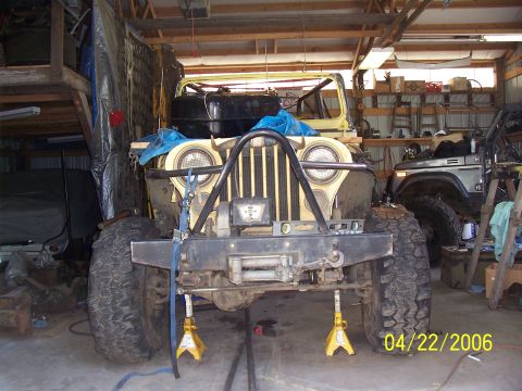 1982 Ford Customline - A yellow Jeep CJ is undergoing maintenance in a garage, with another vehicle visible in the background.