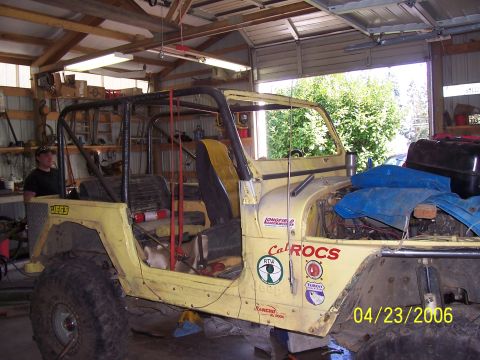 1982 Ford Customline - A yellow Jeep CJ is parked inside a garage with a roll cage and off-road tires.