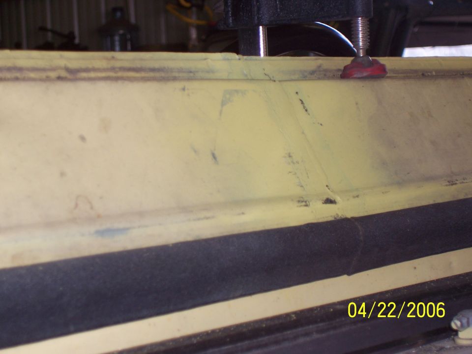 Yellow metal panel with horizontal weld seam and red fastener under machine spindle