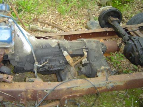 1979 Ford Bronco - Close-up view of a vehicle's transmission and rear axle assemblies resting on the ground outdoors.