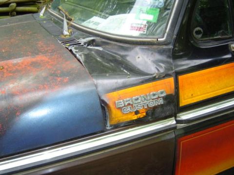 1979 Ford Bronco - The Bronco Custom badge is visible on the side of the vehicle, along with orange and yellow trim.