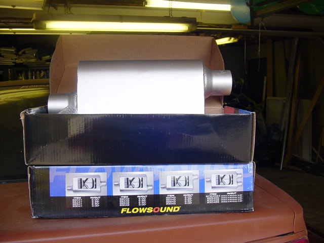 Boxes with Flowsound exhaust mufflers inside, sitting on a car's trunk
