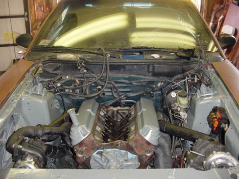 1995 Ford Mustang - The engine bay of a 1995 Ford Mustang shows a V8 engine with twin turbochargers installed.
