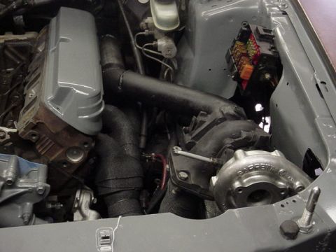 1995 Ford Mustang - Close-up view of a modified engine bay a turbocharger and custom exhaust components.