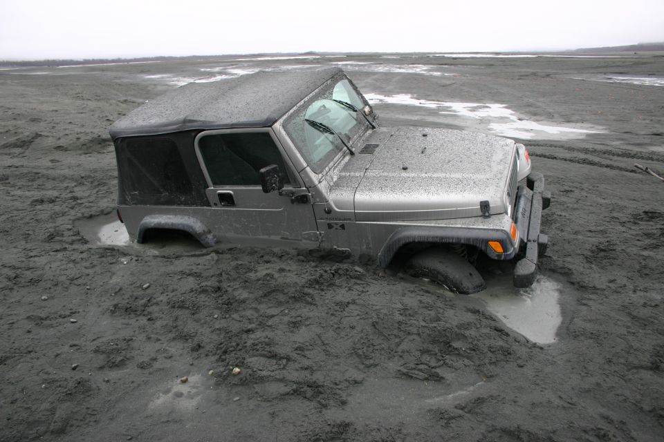 Silver 2003 Jeep TJ stuck in mud, 3q-front view