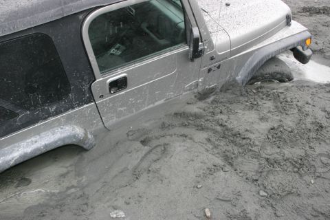 2003 Jeep TJ - This 2003 Jeep TJ is stuck deep in mud, with the front wheel almost completely covered.