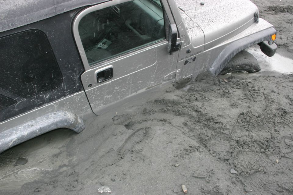 Silver 2003 Jeep TJ stuck in mud, front wheel submerged