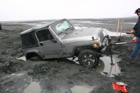 2003 Jeep TJ - Jeep TJ stuck in mud, requiring extraction with tools and assistance.