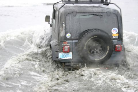 2003 Jeep TJ - A 2003 Jeep TJ navigates through choppy water, its rear end visible as it splashes through the waves.