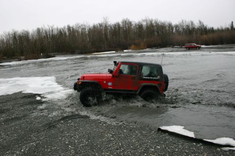 2003 Jeep TJ - A red 2003 Jeep TJ navigates through a watery, icy terrain with a second vehicle visible in the background.