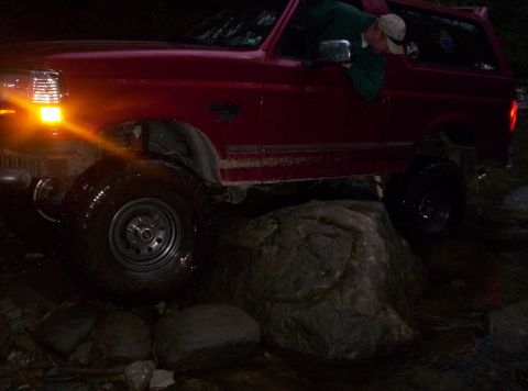 1995 Ford Bronco - Red 1995 Ford Bronco navigates rocky terrain in the dark.