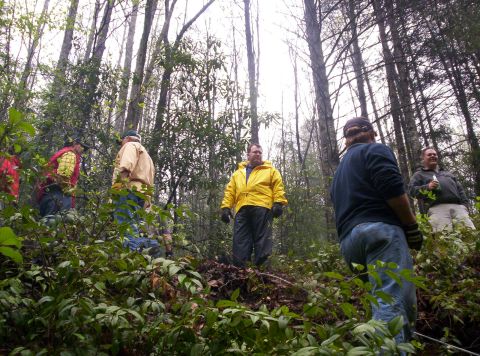 1995 Ford Bronco - A group of men are gathered in a wooded area, possibly on a trail.