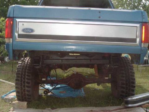 1984 Ford Bronco - Driver's side raised with jack, rear frame painted