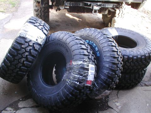 1979 Ford Bronco - A collection of new, off-road tires are ready for installation on a vehicle.