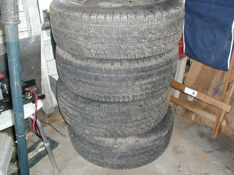 1979 Ford Bronco - A stack of four used tires are stored indoors.
