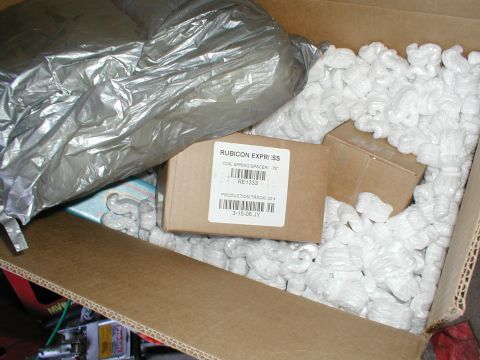 1979 Ford Bronco - A box contains a Rubicon Express coil spring spacer, packed with peanuts and a silver bag.