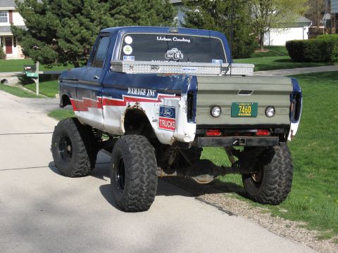 1977 Ford F-150 - This heavily modified pickup truck features a lifted suspension, oversized tires, and a custom paint scheme with 'DAMAGE INC' lettering.