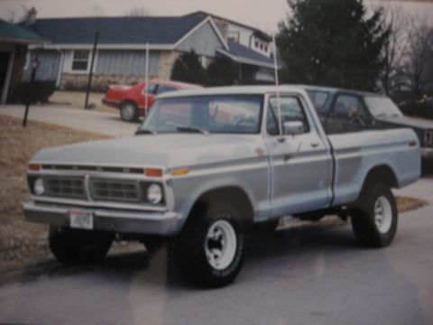 1977 Ford F-150 - This 1977 Ford F-150 pickup truck is shown in a three-quarter front view, with a red car behind it.