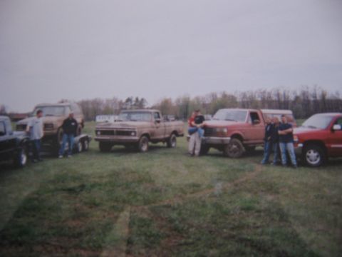 1977 Ford F-150 - A group of people gathered around several trucks and an SUV in an outdoor setting.