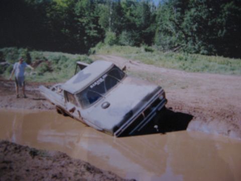 1977 Ford F-150 - A 1977 Ford F-150 is stuck deep in a mud pit with a person standing nearby.