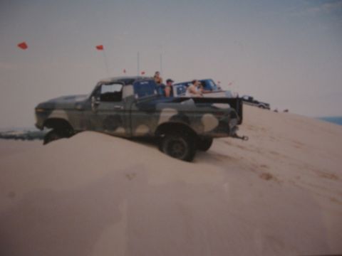 1977 Ford F-150 - Two pickup trucks are on a sand dune, with the front truck partially stuck in the sand.