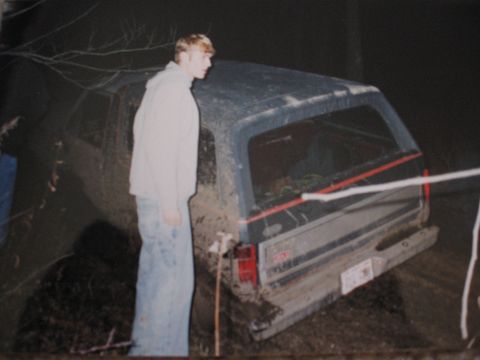 1977 Ford F-150 - A person stands next to a muddy pickup truck that appears to be stuck in the dirt.