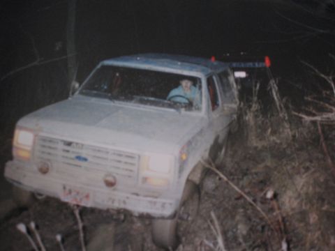 1977 Ford F-150 - A white Ford Bronco II is stuck in the mud at night, with a person in the driver's seat.