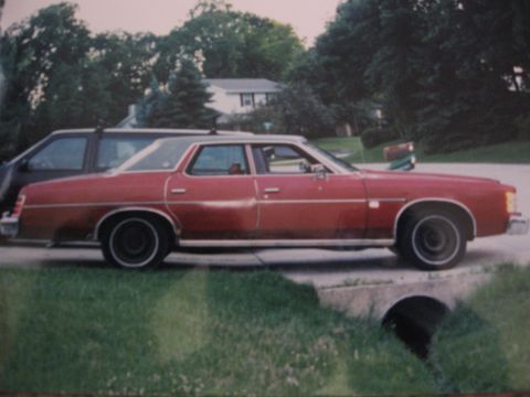 1977 Ford F-150 - Side view of a red sedan parked on a residential street next to another vehicle.