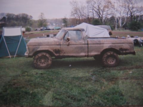 1977 Ford F-150 - A muddy 1977 Ford F-150 pickup truck sits in a grassy field next to a tent.