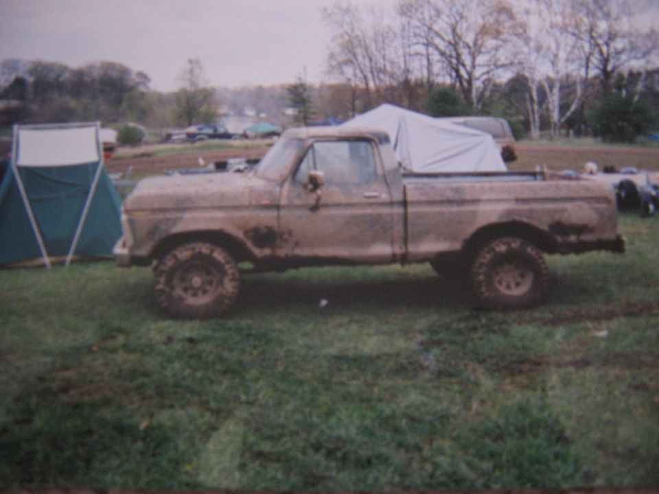 Mud-covered 1977 Ford F-150 pickup truck, side view, with a tarp in the bed