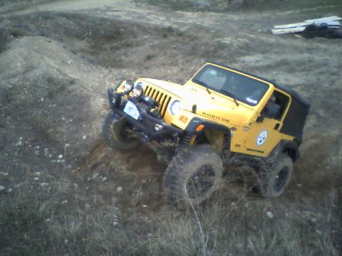 1976 GMC C/K Pickup - A yellow Jeep Wrangler Rubicon navigates a challenging dirt terrain, its off-road capabilities.