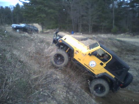 1976 GMC C/K Pickup - Yellow Jeep Wrangler navigating an off-road course with a black SUV visible on a higher incline.
