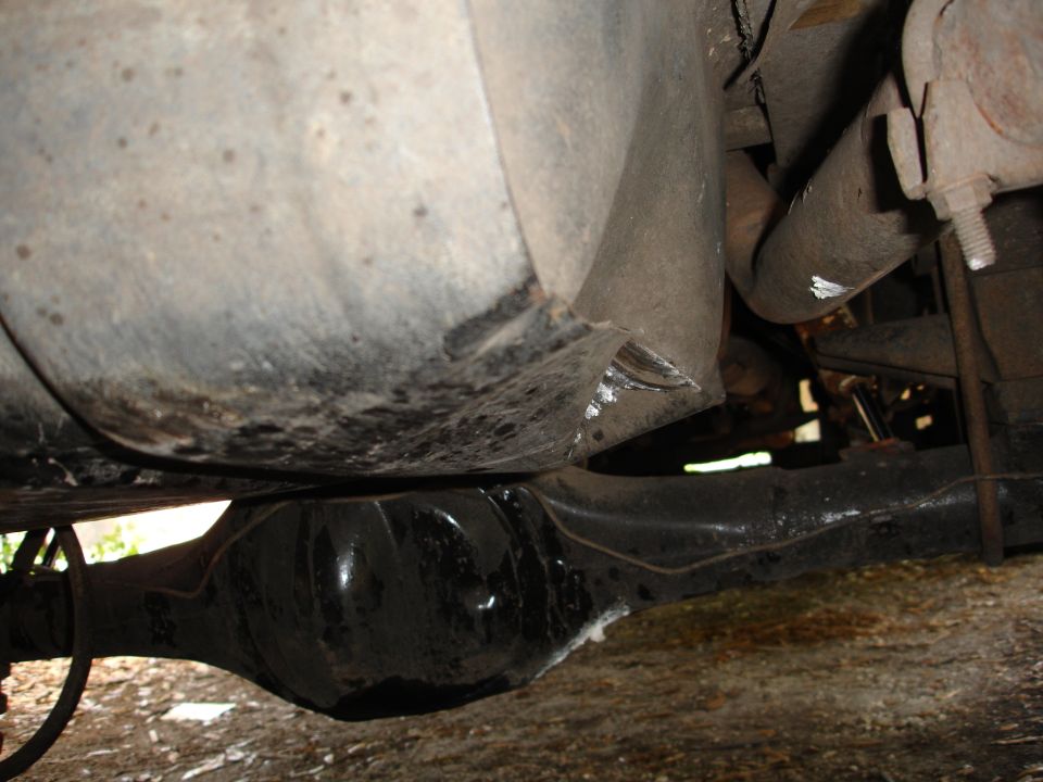 Underside of a vehicle showing a differential and fuel tank. The differential is black and the fuel tank is grey