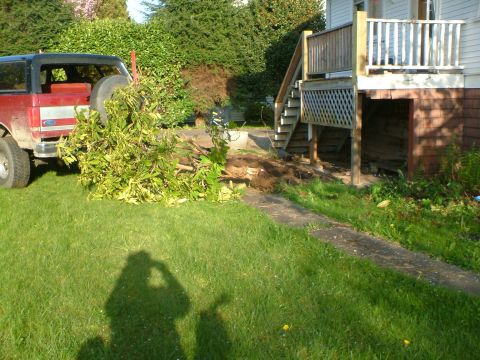 1989 Ford Bronco - A red Ford Bronco is parked on the grass near a house with a wooden deck and stairs.