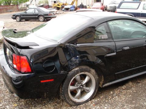 2001 Mercury Grand Marquis - This black coupe shows significant damage to its rear quarter panel and has a racing stripe on the rear window.