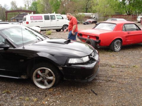 2001 Mercury Grand Marquis - Black Ford Mustang GT shows front-end damage next to a red classic car.