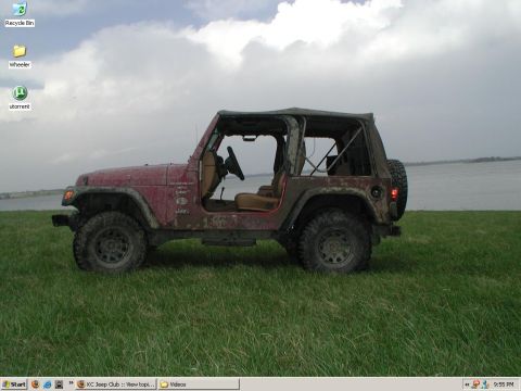 1998 Jeep TJ - Side view of a red 1998 Jeep TJ on a grassy field near the water.