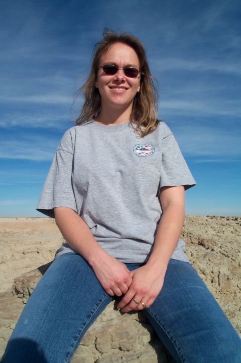 1984 Ford Bronco - Woman sits on rocks under a blue sky with scattered clouds.
