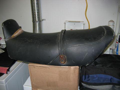 1985 Ford LTD Crown Victoria - This black motorcycle seat features a leather strap and shows signs of wear.